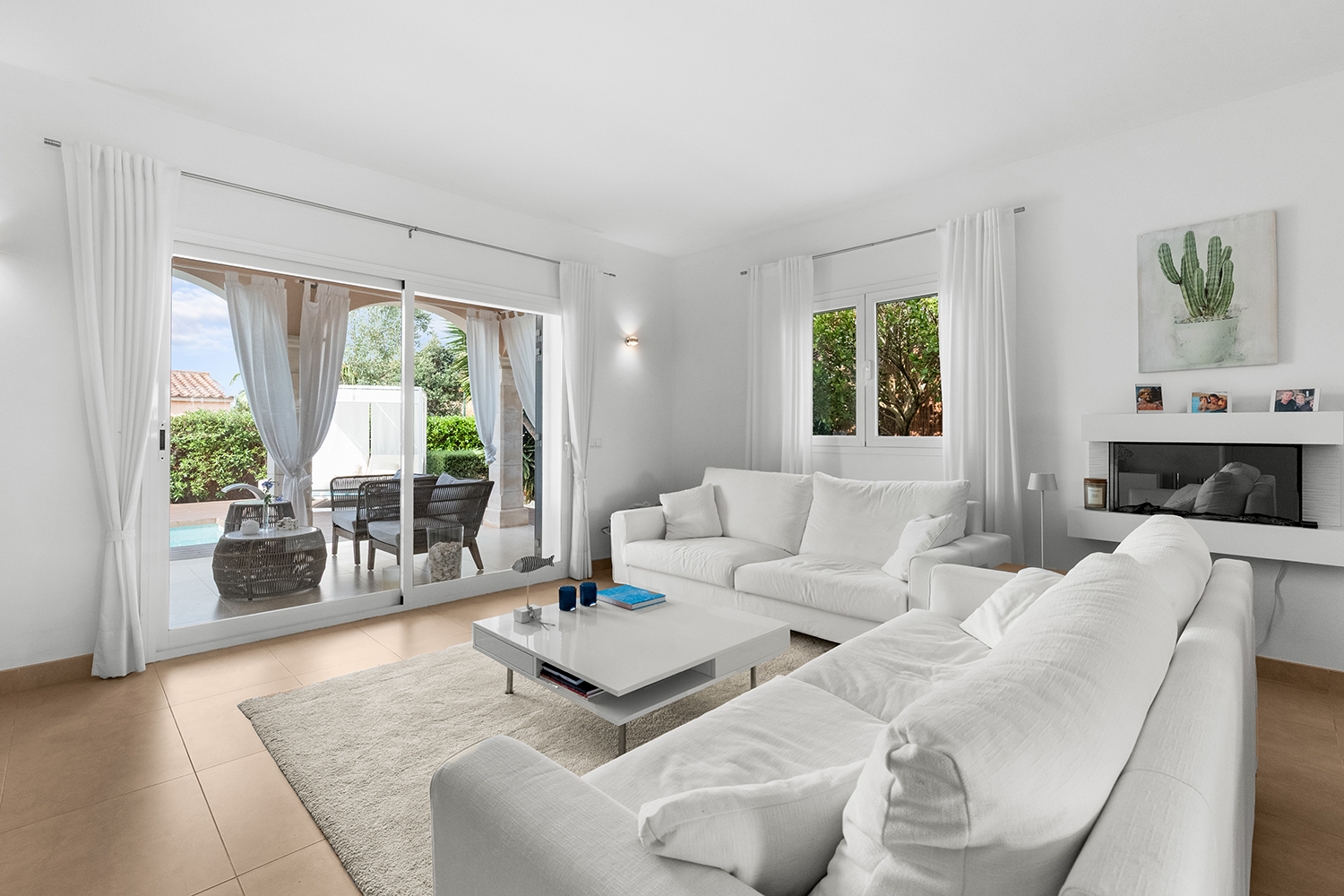 Heller Wohnbereich mit Kamin und Blick zur Poolterrasse