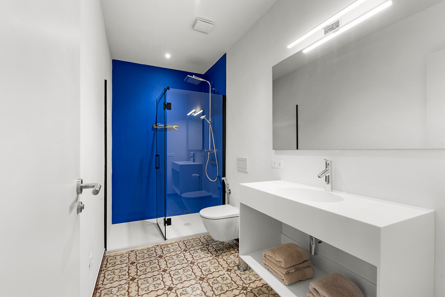 Modernes Badezimmer mit bodengleicher Dusche, Doppelwaschtisch und markanter blauer Akzentwand