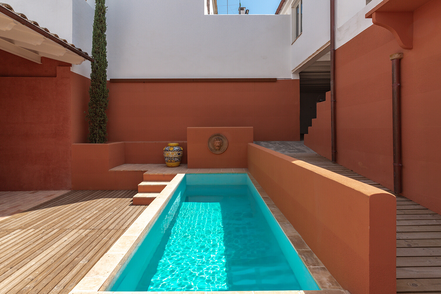 Geschützter Patio mit länglichem Pool und umlaufender Holzterrasse